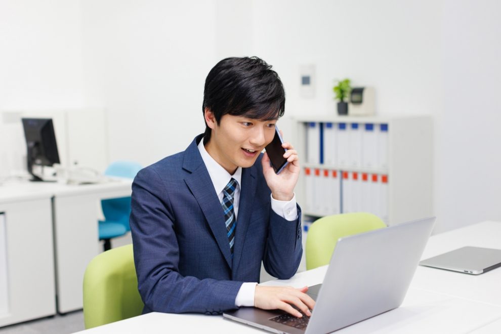 オフィスのデスクで電話する男性